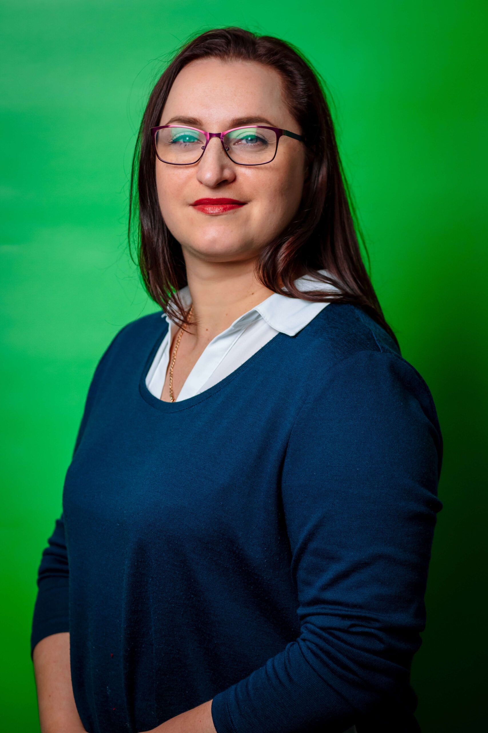Portrait of the manager of Express Heroes, Ms. V. Tseloguz, wearing a dark sweater and white shirt, standing in front of a green background