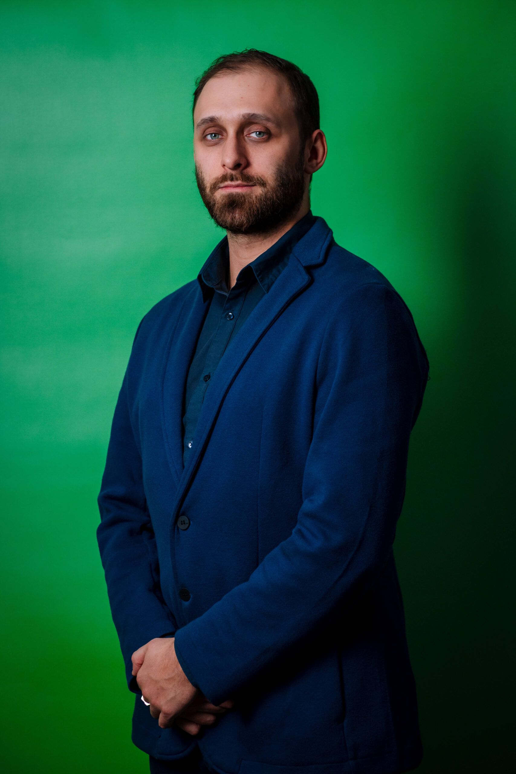 Portrait of the manager of Express Heroes, Mr. K. Hriaznov, wearing a dark suit and dark shirt, with a serious expression on his face, standing in front of a green background.