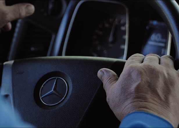Driver holding the steering wheel in a truck cabin during international freight operations with guaranteed mileage for carriers